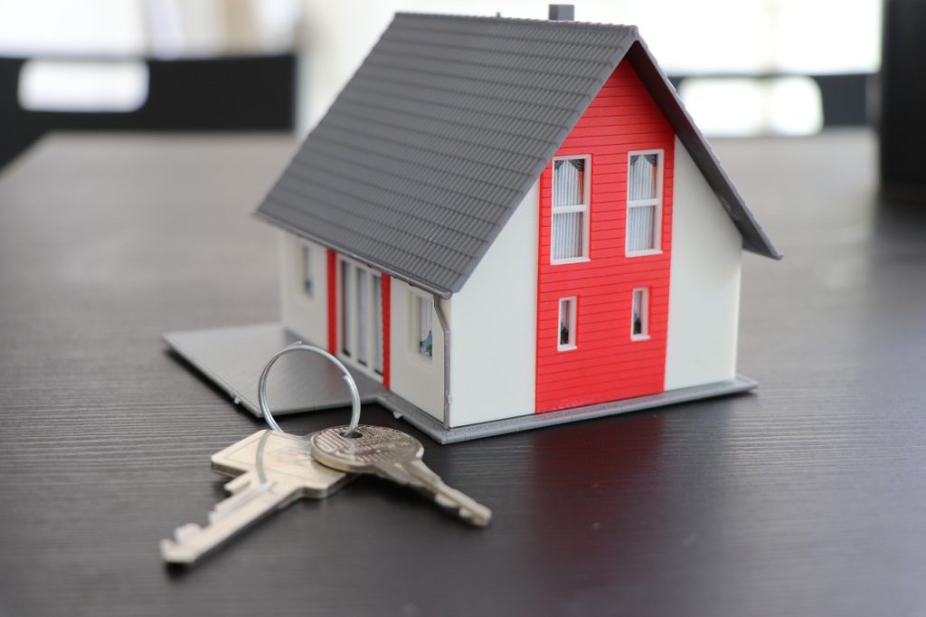 model house displayed on a table alongside a set of keys, symbolising home ownership and security