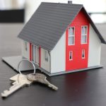model house displayed on a table alongside a set of keys, symbolising home ownership and security