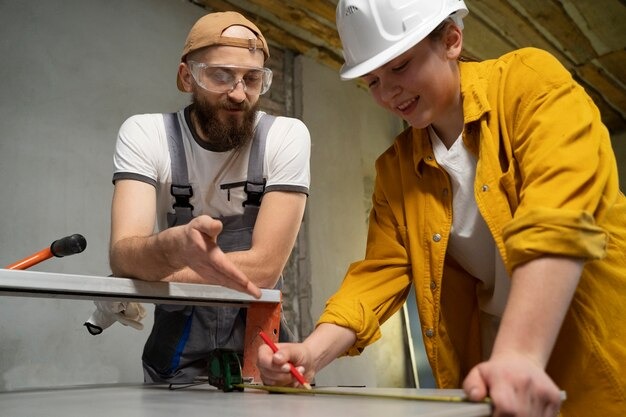 Two individuals collaborating at a table, focused on a project with a tool in use