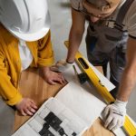 Two construction workers collaborating on a project, reviewing plans and discussing tasks on a job site
